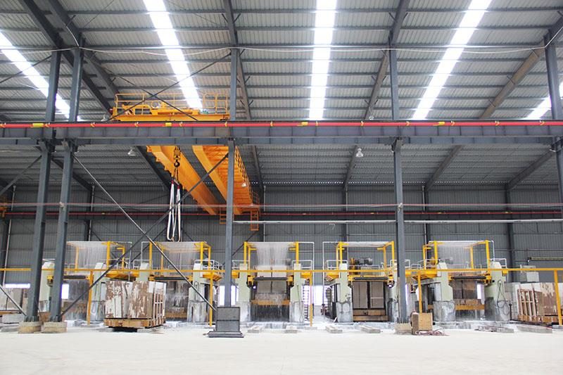 The stone workshop: bridge saws and slabs under a steel roof, from the Door Trim page "Our workshop" section
